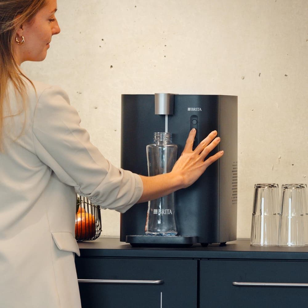 Filling a glass bottle from a mains-fed BRITA water dispenser in an office kitchen
